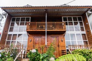 a wooden house with a balcony on top of it at Altura Cabin Dieng in Diyeng