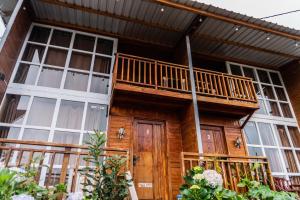 a wooden house with a balcony on it at Altura Cabin Dieng in Diyeng