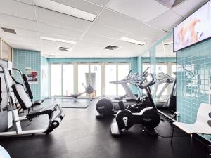 a gym with cardio equipment in a room with blue tiles at Novotel Cairns Oasis Resort in Cairns