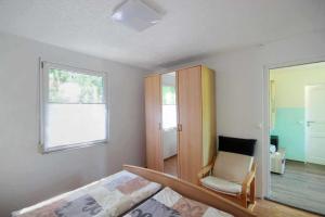 a bedroom with a bed and a chair and a window at Neu Süllitz, Bungalow 50 in Neu Süllitz +2 photos