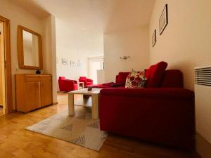 a living room with a red couch and a table at Ferienwohnung Bobtail in Thiessow +8 photos