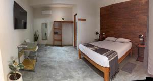 ein Schlafzimmer mit einem Bett und einer Ziegelwand in der Unterkunft Casa Sixta a 7min del aeropuerto internacional PMX y 2 cuadras terminal autob ADO in Puerto Escondido