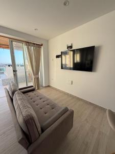a living room with a couch and a flat screen tv at Ballestas Suite in Pisco