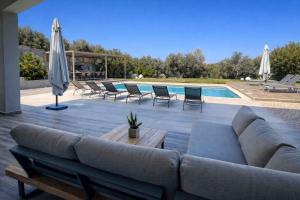 a large couch sitting on a patio next to a pool at Villa Aelia - Modern & Ideal for large groups in Galatás
