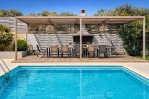 a patio with a table and chairs and a swimming pool at Villa Aelia - Modern & Ideal for large groups in Galatás