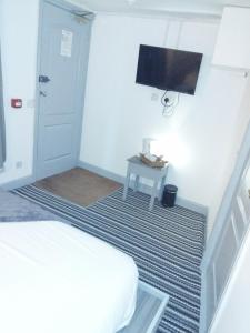 a bedroom with a bed and a tv on the wall at The Commodore Hotel in Nottingham