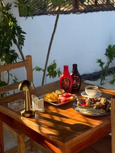 a wooden table with two plates of food on it at Ebruli Guest House in Nungwi