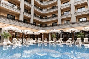 a hotel pool with white chairs and umbrellas at Fafa Sun Hotel - Adults Only in Golem