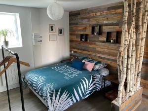 a bedroom with a bed and a wooden wall at Le nid de la Brenne in Luant