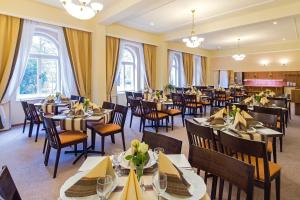 - une salle à manger avec des tables, des chaises et des fenêtres dans l'établissement Dr. Adler Spa & Kurhotel, à Františkovy Lázně