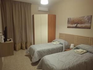 a hotel room with two beds and a television at Dimora Angelica in Statte