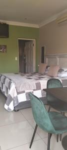 a bedroom with a large bed with two green chairs at SONHOS dreams Self catering Garden Cottages in Bloemfontein