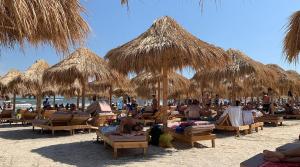 a group of people laying on the beach under straw umbrellas at Zig Zag Apartament in Constanţa