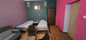 a room with two beds and a couch and a pink wall at Apartament w Centrum Ząbkowic Śląskich z Dwoma Sypialniami in Ząbkowice Śląskie
