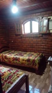 a bedroom with a bed in a brick wall at Chalé Privê Serrano em Gravatá in Gravatá