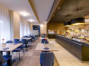 a restaurant with tables and chairs and a kitchen at Mercure Hotel Duisburg City in Duisburg