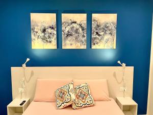 a bedroom with three paintings on a blue wall at Residenza SubitoSanto - Appartamento 1G "Antenore" in Padova