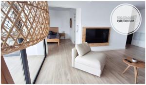 a living room with a white chair and a television at Piso Volcano in Villaverde