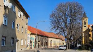 a street in a town with a building and a church at Apartmán Centrum in Komárno