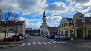 a church with a steeple on a street with cars parked at Apartmán Centrum in Komárno +7 photos