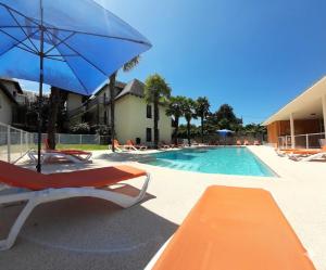 a swimming pool with chairs and an umbrella and a pool at Appartement de la Marmotte Cendrée, dans résidence de tourisme 3 étoiles in Lourdes