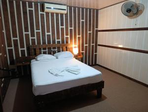 a bedroom with a bed with white sheets and a lamp at Hotel Don Roberto in San Isidro de El General