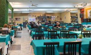 people sitting at tables in a restaurant with blue tables at Hotel Miami in Mar del Plata