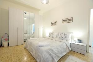 a white bedroom with a large bed and a mirror at La Valletta - Casa di Anna in Menaggio