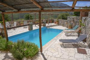 a swimming pool with chairs and a pergola at Traditional Villa with pool in Sfakia in Ímbros