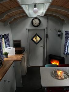 a kitchen with a fireplace and a clock on the wall at Pipowagen in Haaksbergen