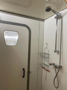 a shower stall with a door and a shower head at Pipowagen in Haaksbergen