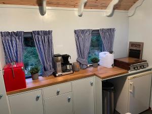 a kitchen with blue and white curtains on the windows at Pipowagen in Haaksbergen +2 photos