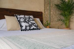 a bed with a black and white pillow on it at Suite Privada Origen 63 Centro Histórico Mérida in Mérida +2 photos