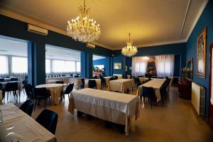 a dining room with tables and chairs and chandeliers at Hotel Rialto Suisse in Lido di Camaiore