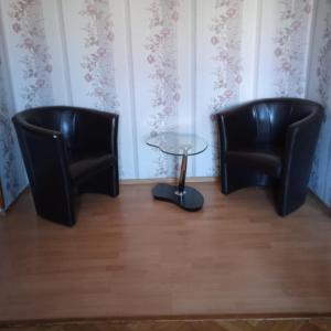 two black chairs and a glass table in a room at Gościnne Gniazdo in Będzin