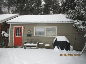 a small house with a red door in the snow at Bunkhouse on Bomoseen in Castleton