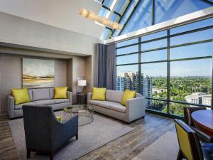 a living room with couches and a large window at Novotel Toronto North York in Toronto