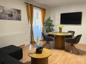ein Wohnzimmer mit Tisch, Stühlen und Fernseher in der Unterkunft Filuma Suite - Riverside Terrace on Gacka River in Otočac