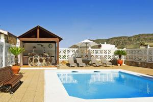 a swimming pool on a patio with chairs and an umbrella at Casa Rural Milagrosa in Valsequillo