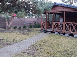 a wooden cabin with a porch in a yard at Domek letniskowy in Wójcin