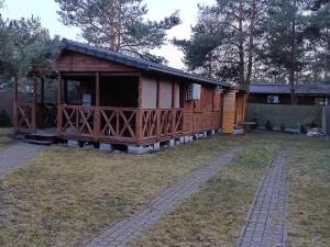 a large wooden cabin with a porch in a yard at Domek letniskowy in Wójcin