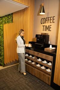 a woman standing in front of a coffee time counter at Hotel Continental ByHours in Bogotá