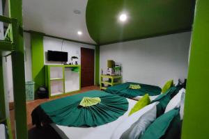 two beds in a room with green and white at MilVir Tourist Inn El Nido near Beach in El Nido