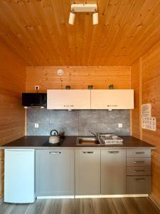 a kitchen with white cabinets and a wooden ceiling at Morska Melodia in Sarbinowo +11 photos