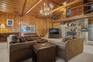 a living room with couches and a stone fireplace at Crystal Creek Chalet - Meredith Lodging in Welches