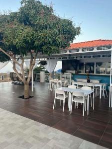 a restaurant with white tables and chairs and a tree at Hotel Pousada Venus in São Filipe