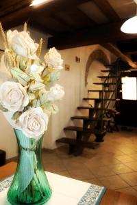 a green vase filled with white roses on a table at Casa Vacanze Sotto Piazza in Gualdo Tadino