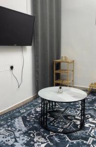 a room with a table and a tv on a wall at Elite Apartment in Nizwa
