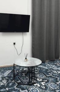 a room with a table and a tv on a wall at Elite Apartment in Nizwa