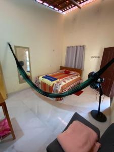 a hammock in a room with a bed in it at Pousada da vila in Beberibe